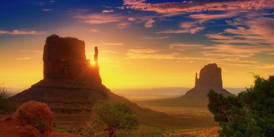 Monument Valley, Arizona sunset behind a rock cliff.