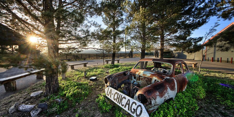 An old rusty car sits on Route 66.
