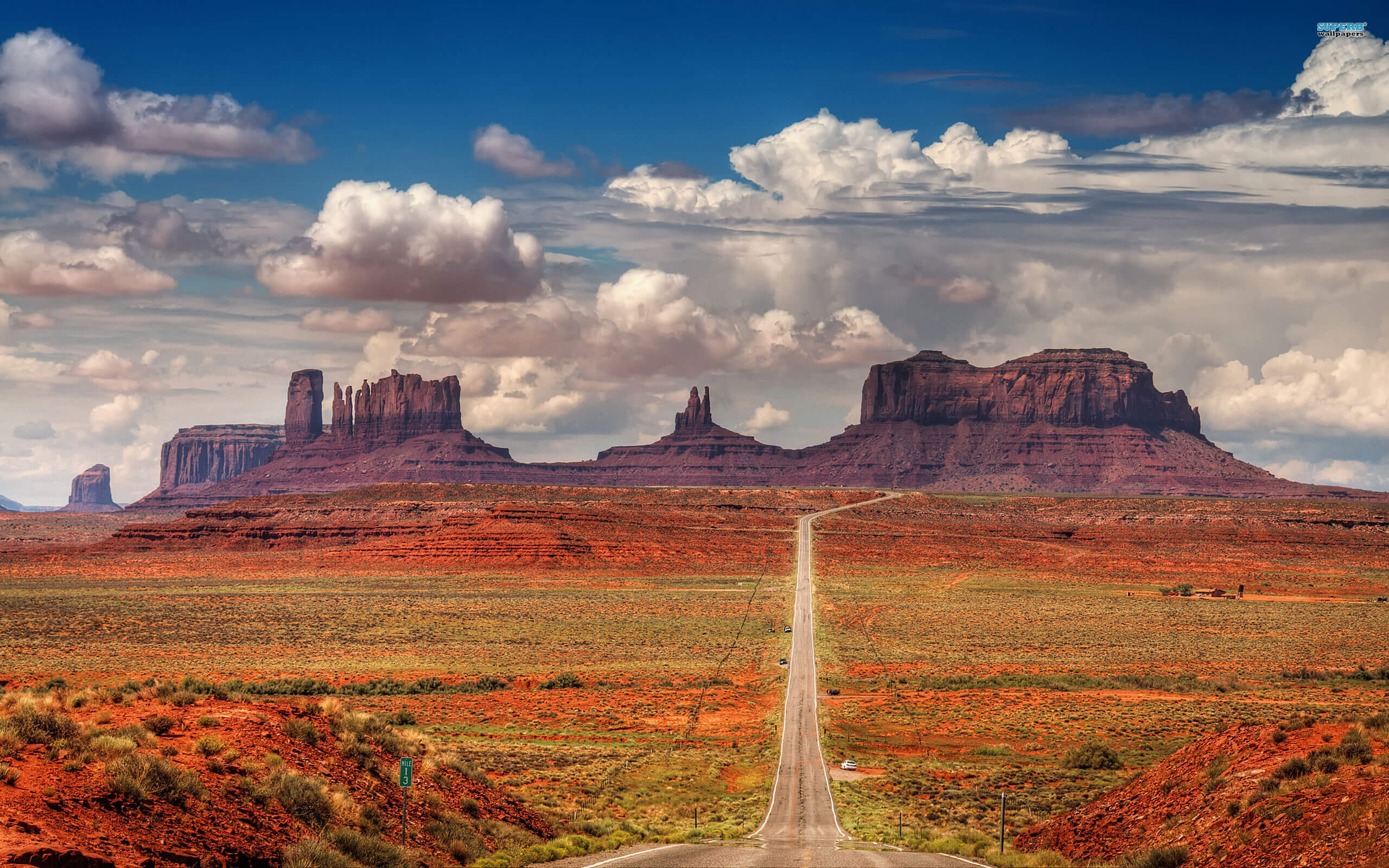 Monument Valley in the background and a road to it in the foreground. 