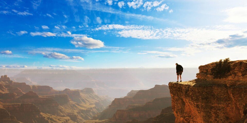 A hiker stands on the edge of the Grand Canyon.