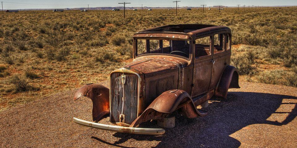 An old rusted automobile sits out in the Arizona desert.