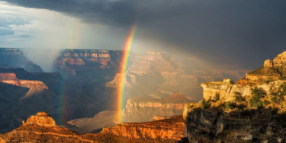 A picture of a rainbow straight down into the Grand Canyon.