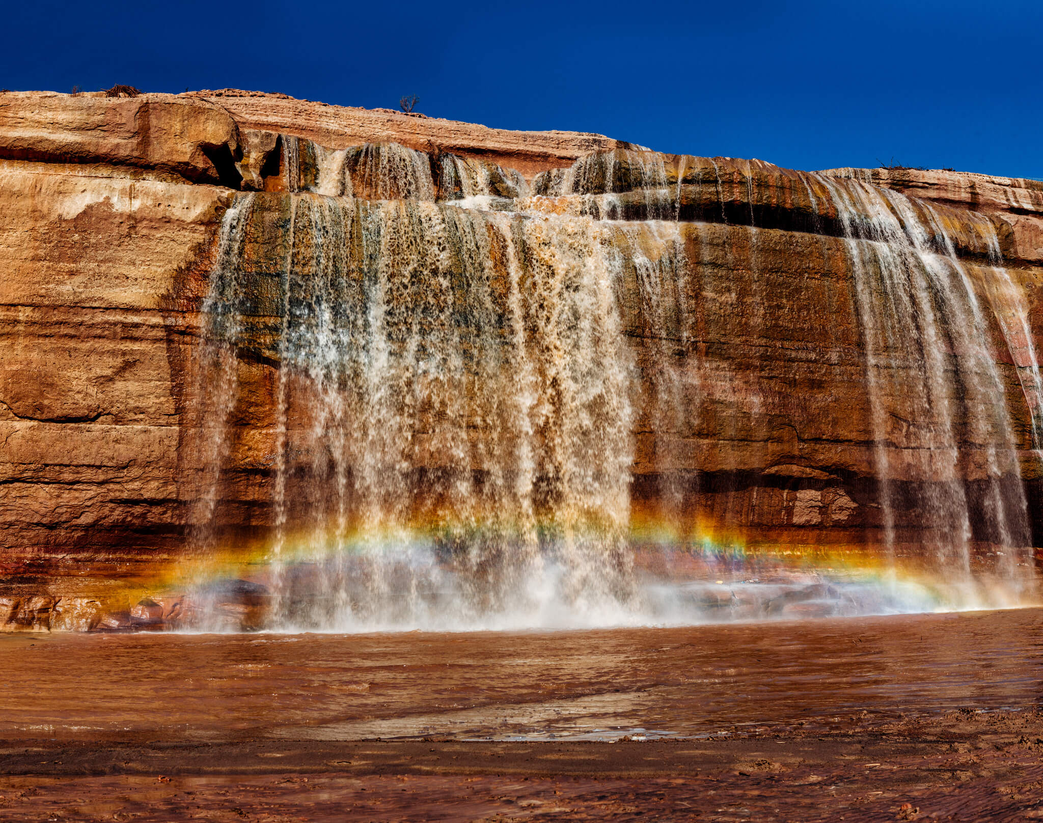 A rainbow shines through the chocolate colored Grand Falls in Arizona.