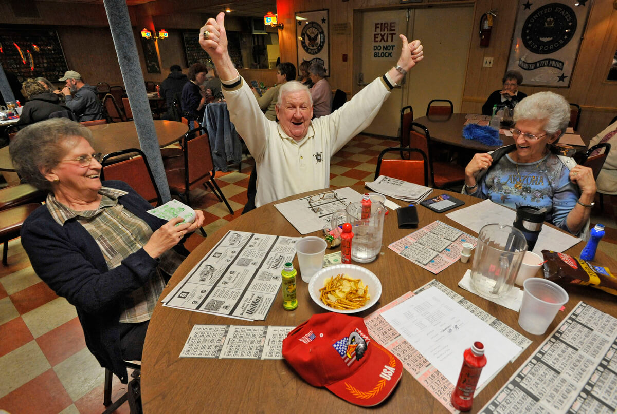 Rosedale, MD -- 2011 -- Bill James, 80, of Rosedale, center, celebrates after winning $95 in a "full card" game, as his wife Mary James, 76, left, and friend Thelma Sutphin, 68, of Middle River, look on, at VFW Post 6506. The VFW Post wanted to hold casino nights with card games and roulette to raise more money, if the legislature approved an expansion of gambling. (Amy Davis / Baltimore Sun)