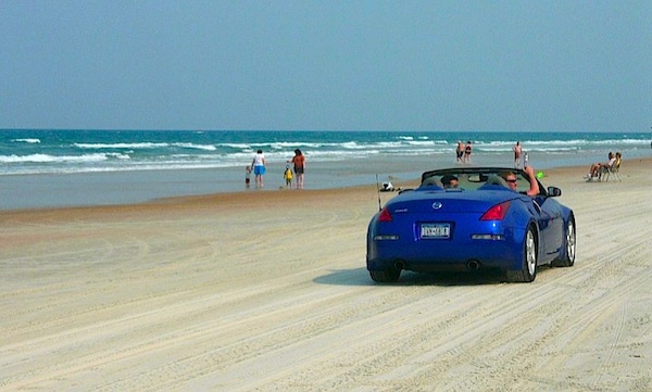 North Carolina is famous for their beaches like this one with a blue convertible driving on it.