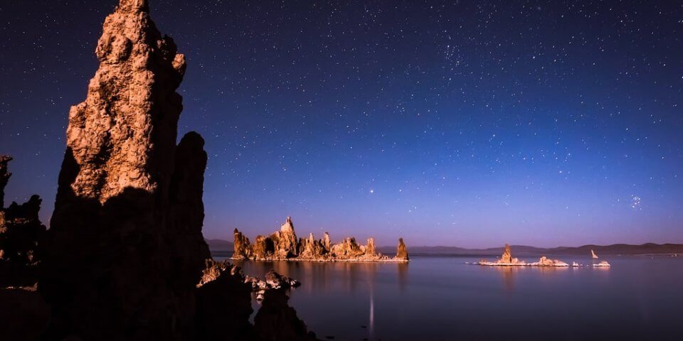 Stars appear in the dark-blue night sky above rock formations in Mono Lake. 