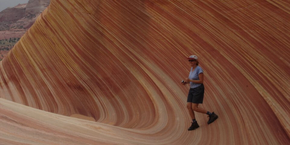 A middle-age woman hiking along The Wave in the Vermilion Cliffs of Arizona.