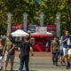 A vibrant outdoor market scene with numerous people walking and browsing stalls under a canopy of trees, featuring the Portland Saturday Market.