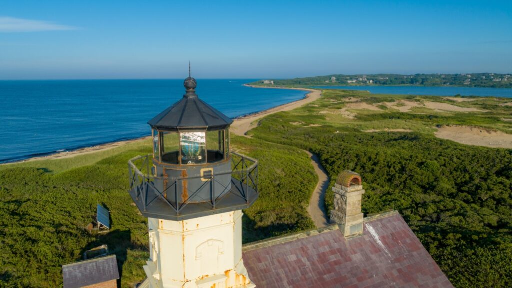 Block Island North Light lighthouse on a sandy point with ocean and land visible. 